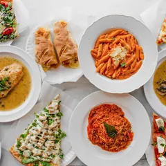 Catering spread of pasta, chicken, salads and pizza